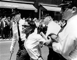 Civil Rights protester being restrained by three police officers.