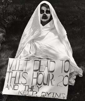 Vietnam War protester with a painted face and wearing a white sheet symbolizing a ghost and the casualties of the war.