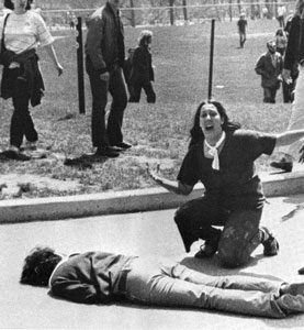Woman crying behind one of the fallen victims of the Kent State shootings involving the Ohio National Guard.