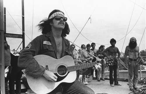 Country Joe performing at Woodstock with his acoustic guitar.