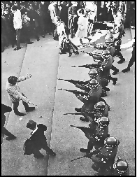 Vietnam War protester gesturing a hug with arms wide open to a line of National Guardsmen.