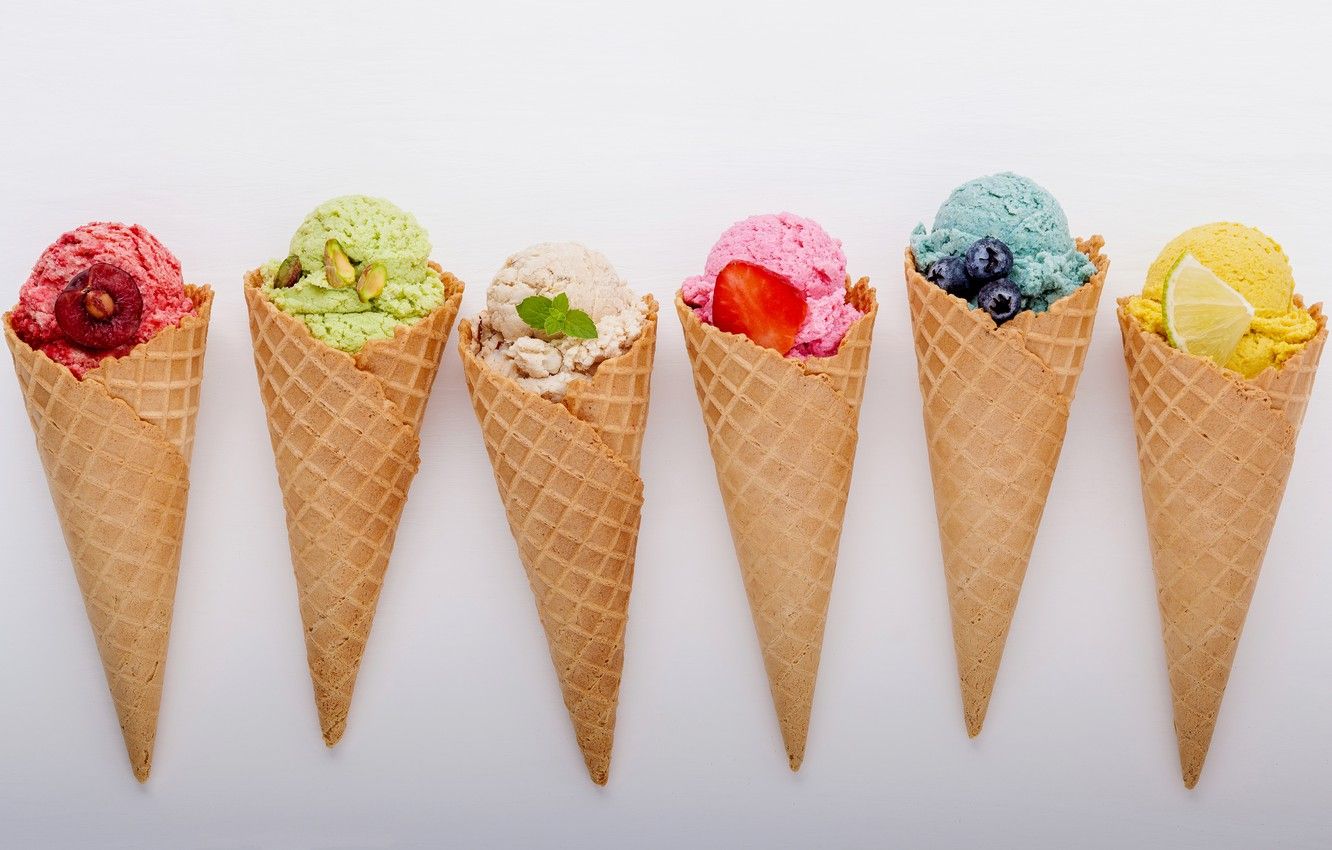 Row of six colorful ice cream cones. From left to right, red, green pistachio, white, pink strawberry, blue blueberry, and yellow lemon