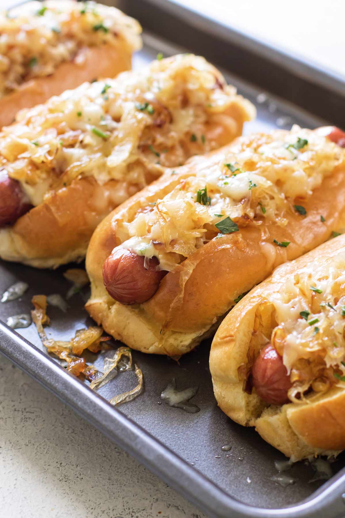 Close up of three hot dogs side by side with chopped onion on top